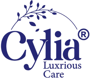The logo for Cylia Luxrious Care, featuring the brand name in dark blue serif lettering with a decorative leafy branch arching over the wordmark, set against a transparent checkered background.
